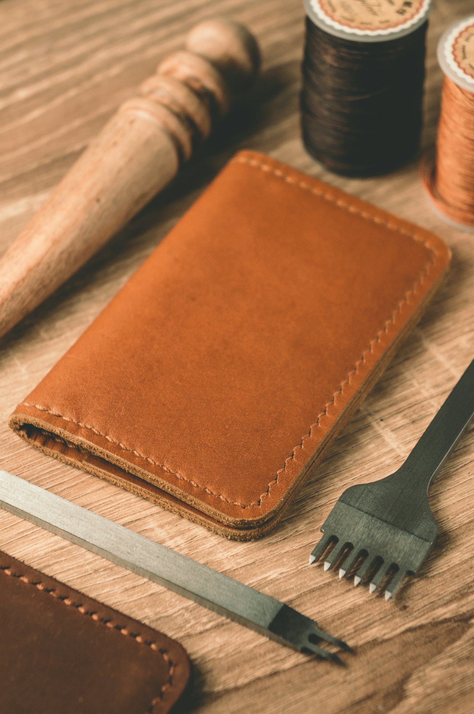 A hand-stitched leather piece resting among an artisan's tools